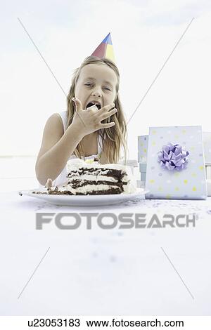 Stock Image - Young girl eating birthday cake. Fotosearch