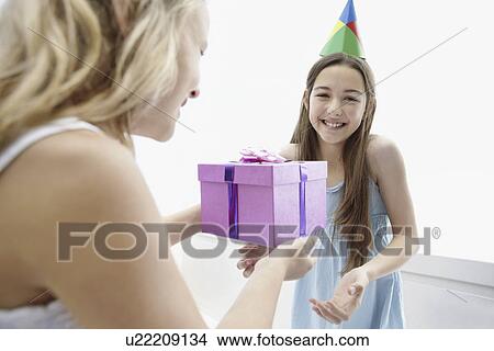 Young girl giving a birthday present to her friend View Large Photo Image Picture - Young girl giving a birthday present to her friend. Fotosearch