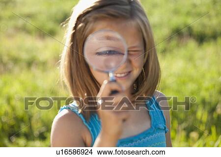 Picture - Young girl holding a magnifying glass. Fotosearch