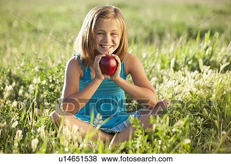 Young girl holding an apple View Large Photo Image Stock Photo - Young girl holding an apple. Fotosearch