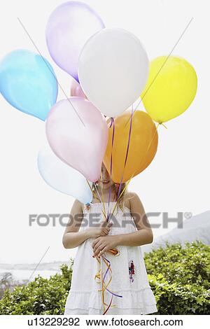 Stock Image - Young girl holding balloons. Fotosearch
