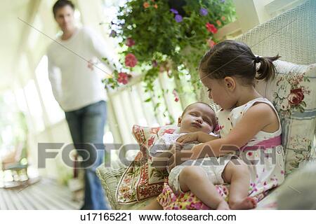 Stock Image - Young girl holding her baby sister. Fotosearch