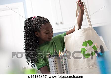 Stock Photo - Young girl holding reusable shopping bag. Fotosearch