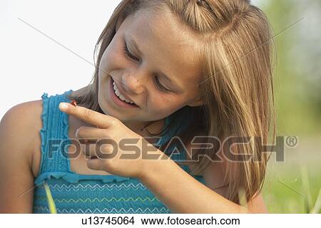 Picture - Young girl looking at a ladybug. Fotosearch