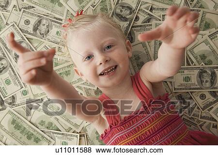 Stock Photo - Young girl lying on a pile of money. Fotosearch