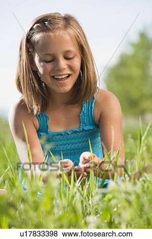 Stock Photo - Young girl playing in grass. Fotosearch
