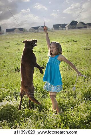 Stock Image - Young girl playing with her dog. Fotosearch