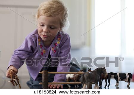 Picture - Young girl playing with toy animals. Fotosearch