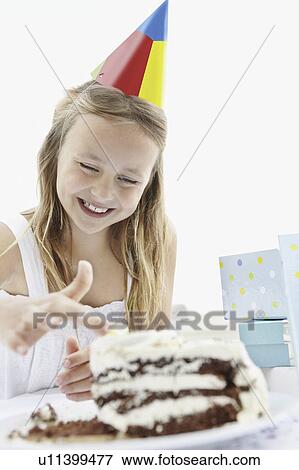 Stock Photo - Young girl putting her finger in icing on birthday cake. Fotosearch