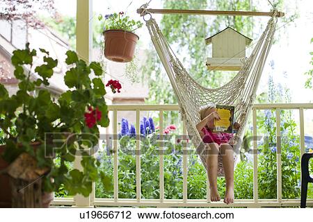 Stock Image - Young girl reading in hammock. Fotosearch