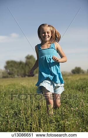 Stock Image - Young girl running in field. Fotosearch