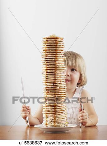Young girl sitting behind a tall stack of pancakes View Large Photo Image Stock Photo - Young girl sitting behind a tall stack of pancakes. Fotosearch