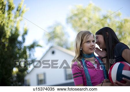 Young girl whispering to her friend View Large Photo Image Stock Photography - Young girl whispering to her friend. Fotosearch