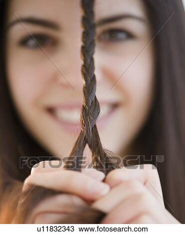 Stock Image - Young woman braiding her hair. Fotosearch