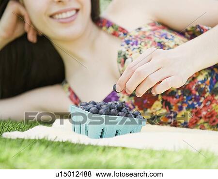 Stock Photo - Young woman eating blueberries. Fotosearch