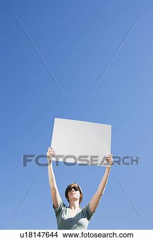 Young woman holding a blank placard View Large Photo Image Picture - Young woman holding a blank placard. Fotosearch