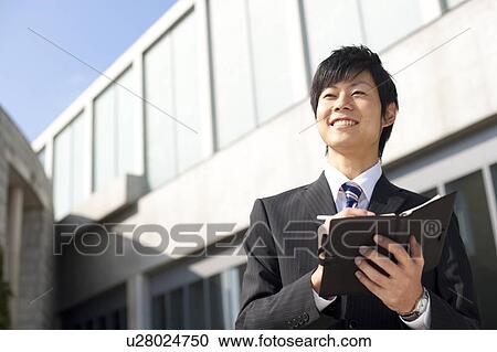 Stock Image - A businessman holding a notebook. Fotosearch