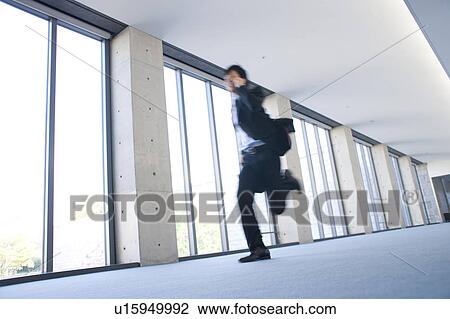 A businessman holding cellphone and running View Large Photo Image Stock Image - A businessman holding cellphone and running. Fotosearch