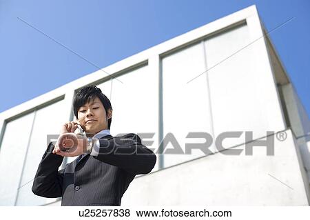 A businessman on the phone and looking at a watch View Large Photo Image Stock Photo - A businessman on the phone and looking at a watch. Fotosearch
