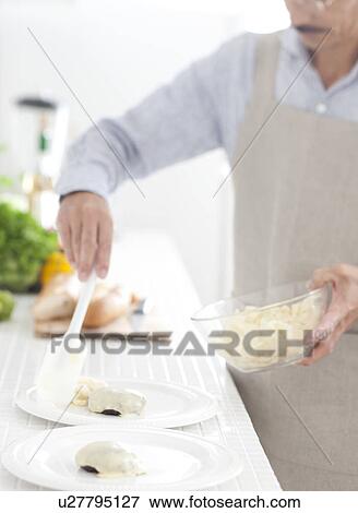 Stock Photo - A man putting hamburger stake on the plates. Fotosearch