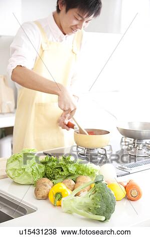Stock Photo - A young man cooking. Fotosearch