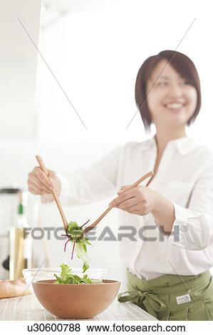 Stock Photo - A young woman making salad. Fotosearch