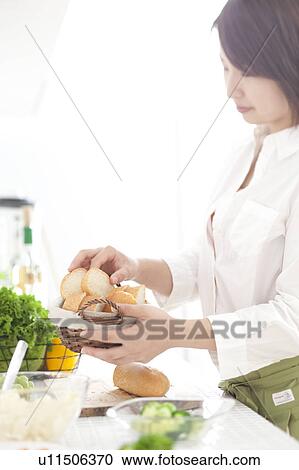 Stock Image - A young woman preparing meal. Fotosearch