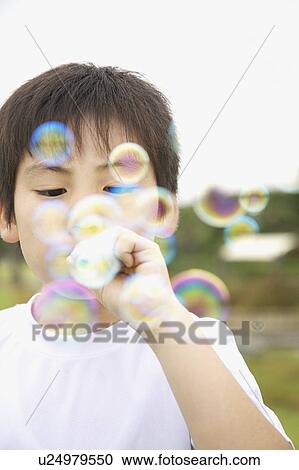 Stock Image - Boy blowing bubbles, Kanagawa Prefecture, Honshu, Japan. Fotosearch