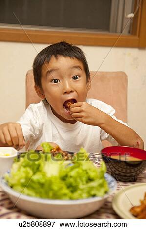 Stock Photo - Boy eating fried chicken, Japan. Fotosearch