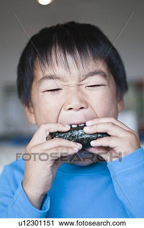 Stock Image - Boy eating rice ball, Japan. Fotosearch