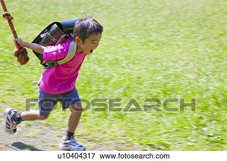 Stock Photo - Boy holding a rope and running, Japan. Fotosearch