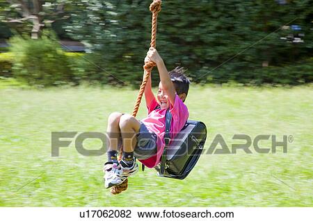 Stock Image - Boy on rope swing, Japan. Fotosearch