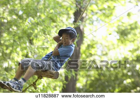 Stock Photo - Boy on tree swing, smiling. Fotosearch