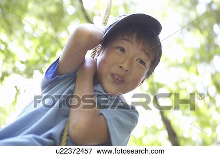 Stock Photo - Boy on tree swing, smiling. Fotosearch