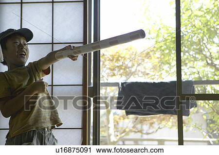 Stock Image - Boy pointing forward with stick, smiling. Fotosearch