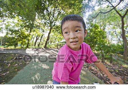 Stock Image - Boy riding a bicycle at a park, Japan. Fotosearch