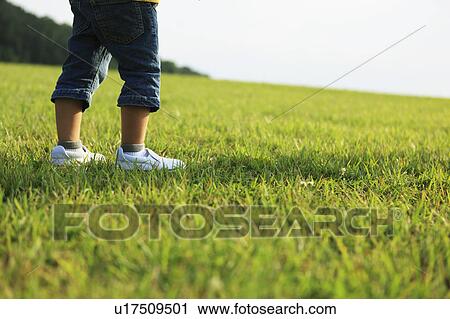 Stock Image - Boy Standing on Grass, Low Section. Fotosearch