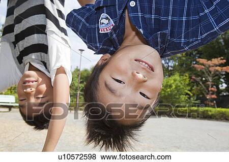 Stock Photo - Boys hanging from the gymnastics bar, Japan. Fotosearch