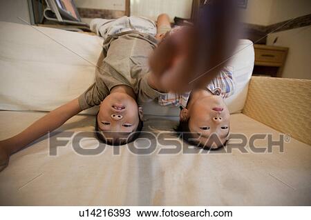 Stock Image - Boys performing headstand on sofa, Japan. Fotosearch