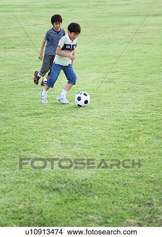 Picture - Boys playing soccer in field, copy space. Fotosearch