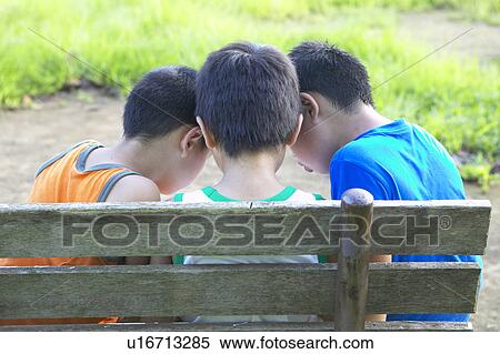Boys sitting on bench, looking down View Large Photo Image Stock Photography - Boys sitting on bench, looking down. Fotosearch