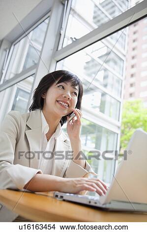 Businesswoman Talking on the Phone and Using Laptop View Large Photo Image Picture - Businesswoman Talking on the Phone and Using Laptop. Fotosearch