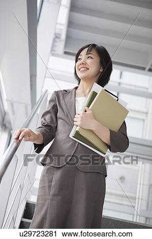 Stock Image - Businesswoman Walking Down Stairs. Fotosearch
