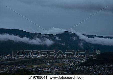 Stock Image - City by Mountain Range at Night. Fotosearch