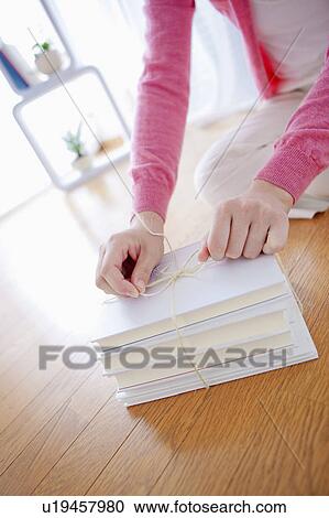 Stock Image - Close up of Woman Tying Books Together. Fotosearch