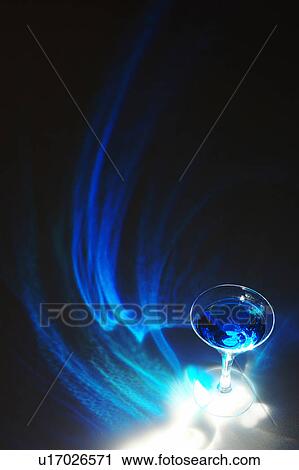 Stock Image - Cocktail glass, black background, long exposure. Fotosearch