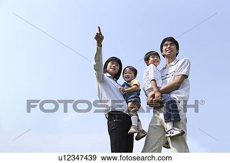 Stock Photo - Family with Two Children Standing Under Clear Sky. Fotosearch