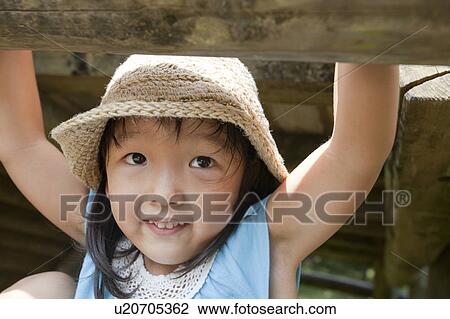 Stock Image - Girl handing from jungle gym, Japan. Fotosearch