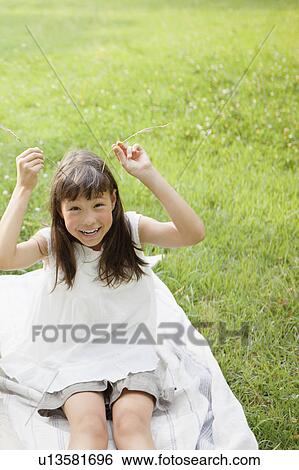Stock Photograph - Girl Holding Hay Stems on her Head as Horns. Fotosearch