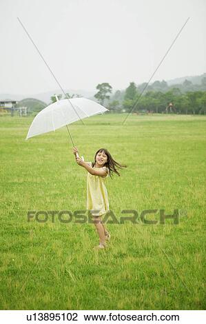Stock Image - Girl Holding Umbrella in Wind. Fotosearch